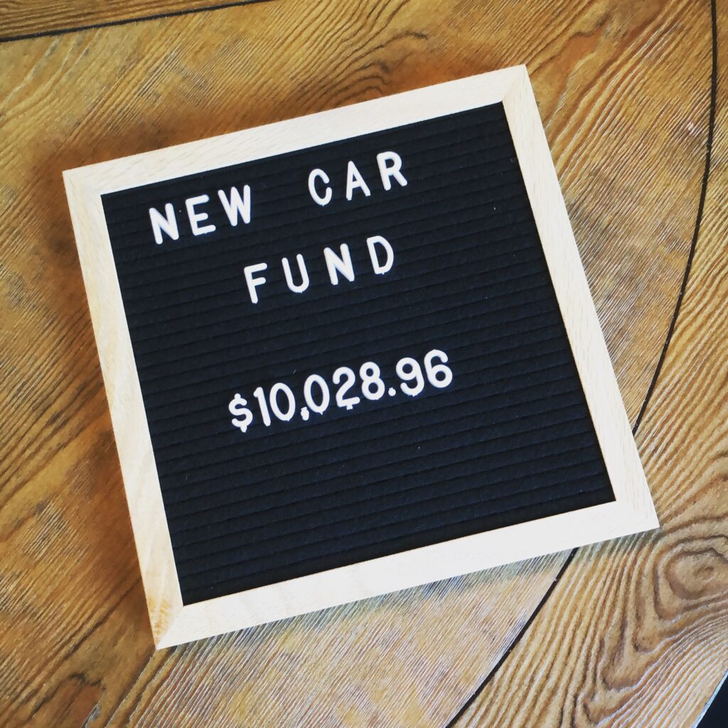 letter board sign with the words new car fund and a savings amount