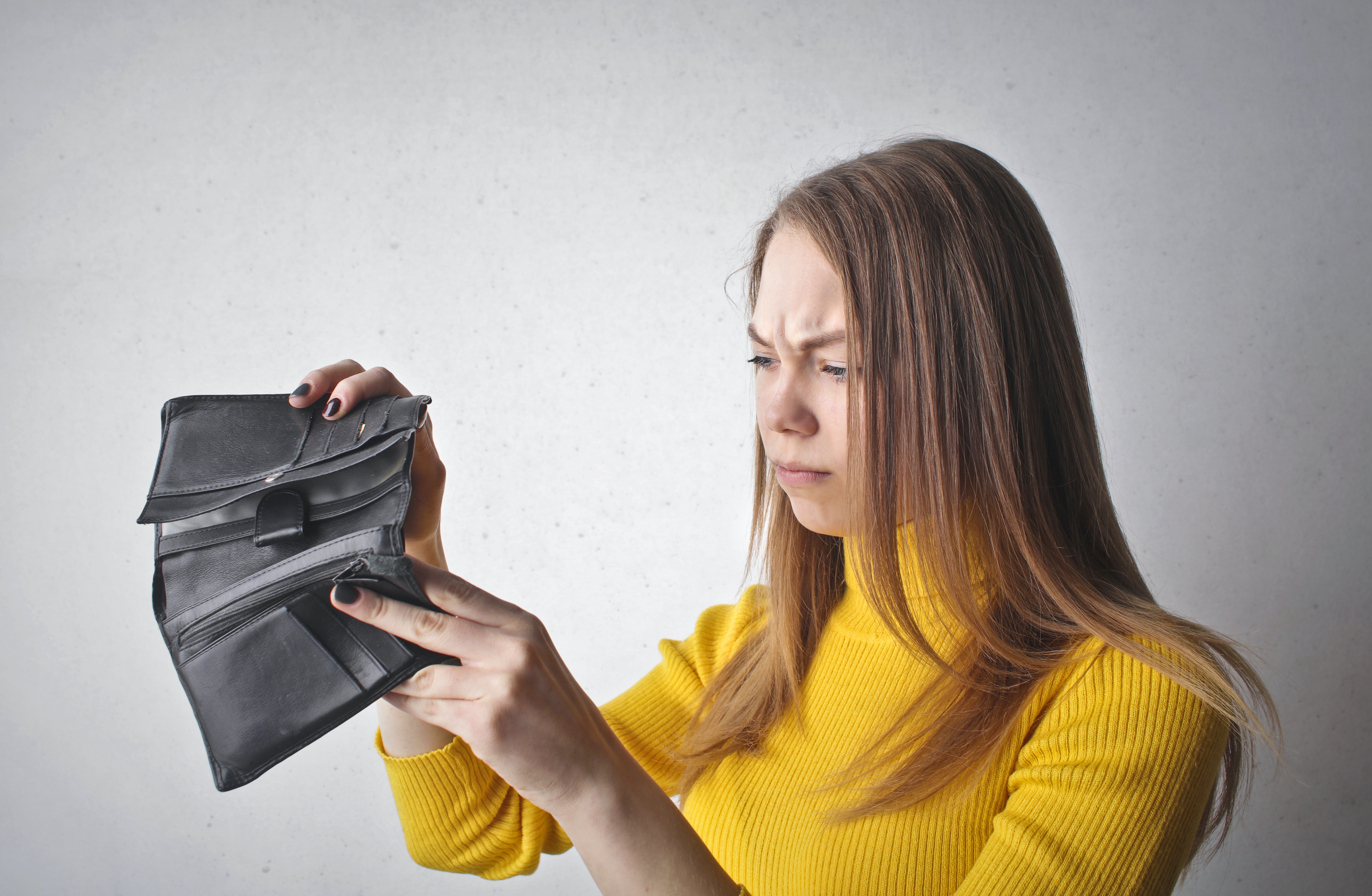 women holding an empty wallet looking confused