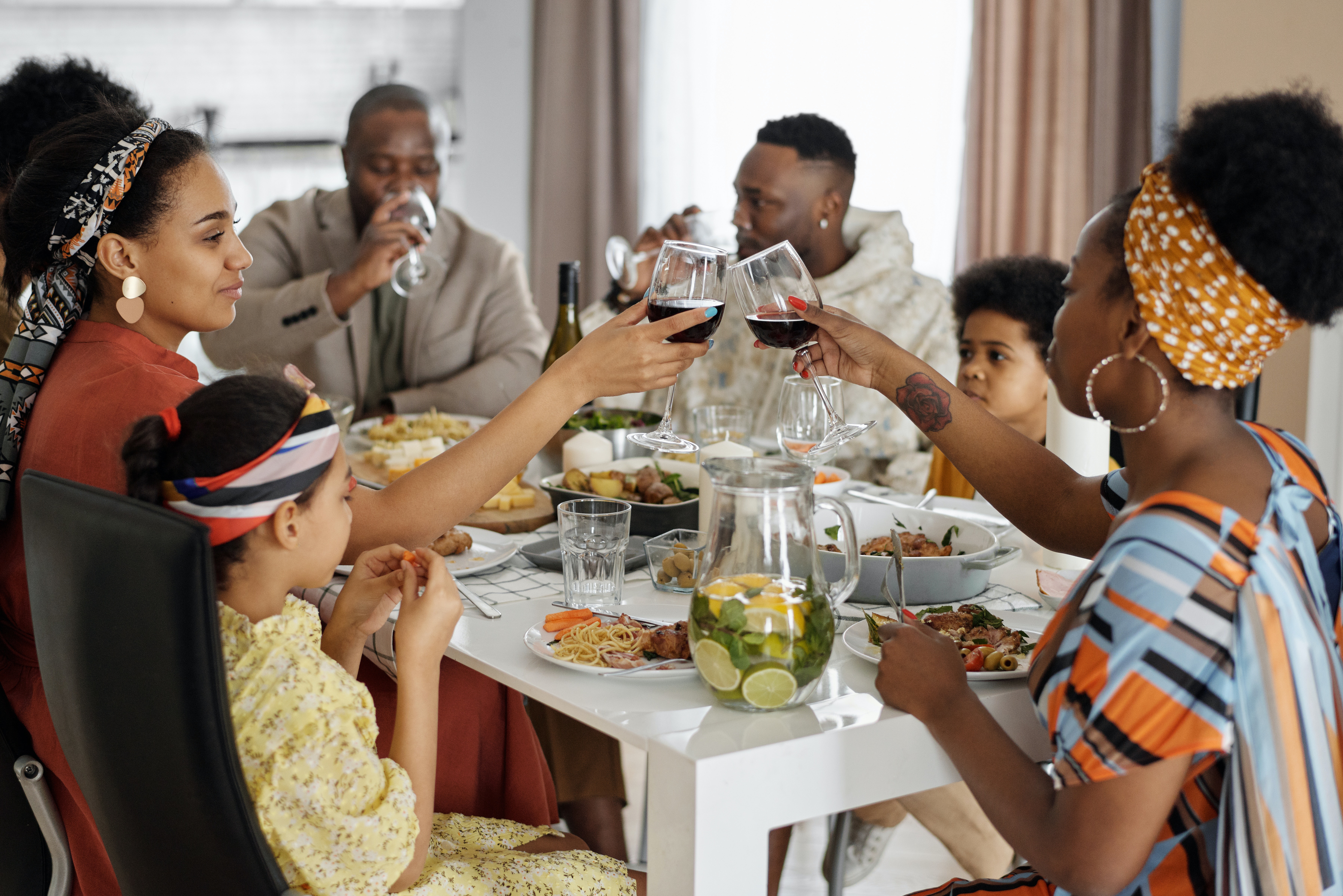 large family eating at the dinner table cheering and drinking wine 