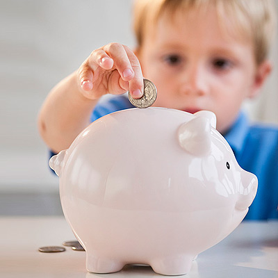 little boy putting change in a piggy bank